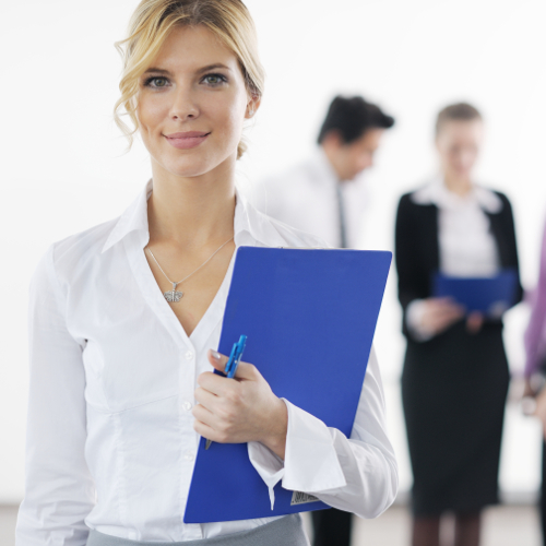 Successful business woman standing with her staff in background at modern bright office